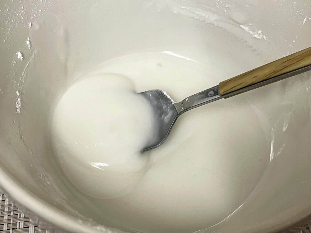icing sugar mixed with water in a small white bowl with a spoon.