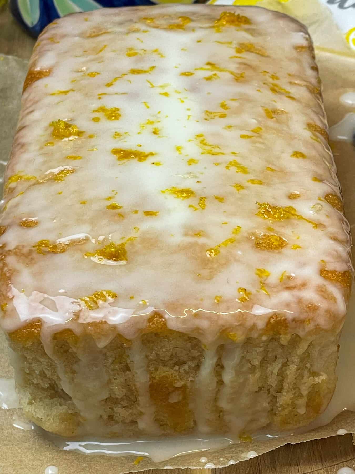 vegan lemon drizzle cake close up on wooden board, featured image.