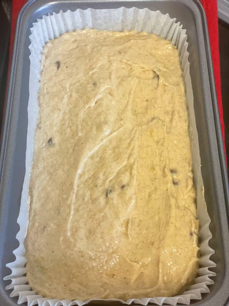 Unbaked banana bread in a 2 pound loaf pan with paper case insert.