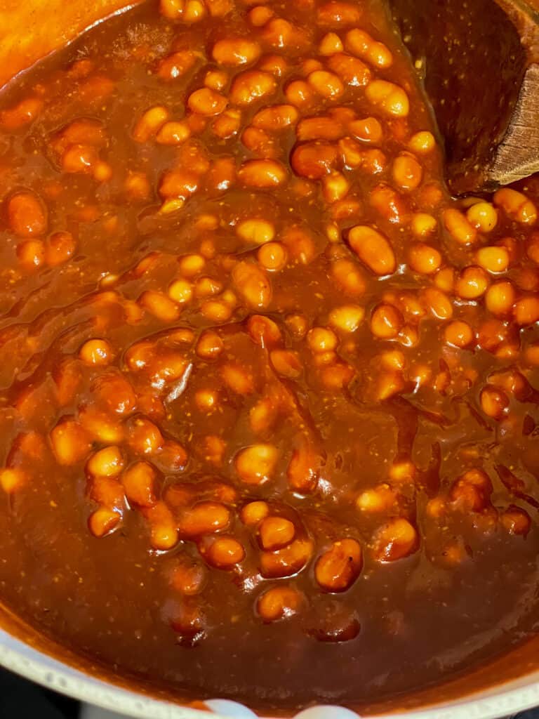 beans mixed with tomato and flavourings in pot.