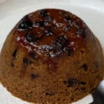 steamed syrup and date pudding on white plate.