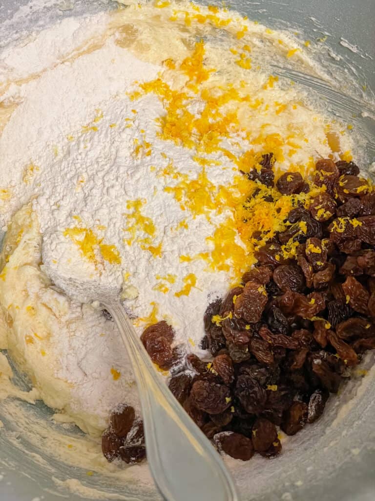 lemon zest, flour, baking powder and raisins added to the creamed margarine in the mixing bowl with a spoon.