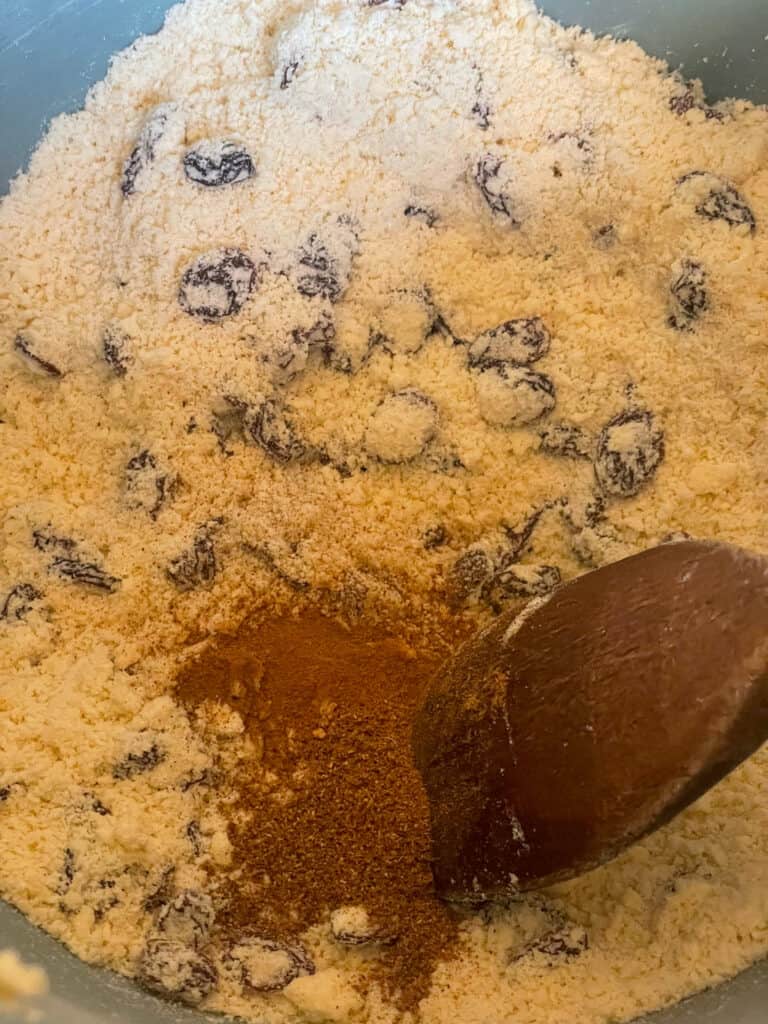 mixed spice and raisins added to breadcrumb mix and stirred with wooden spoon.