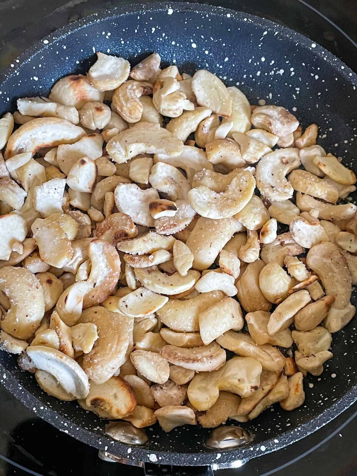 cashew nuts toasting in small non-stick pan.