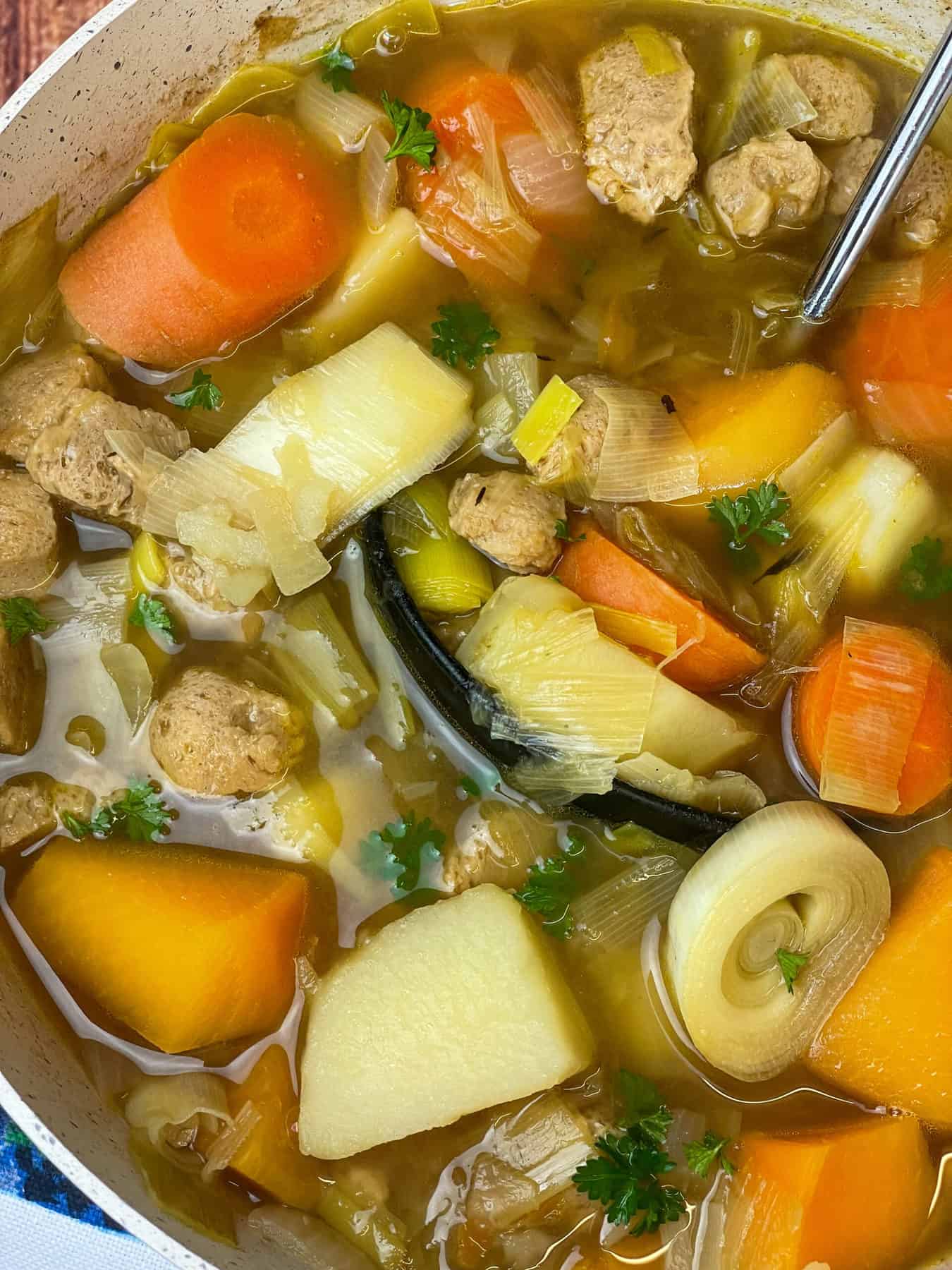 A close up side view of Cawl soup in soup pan.