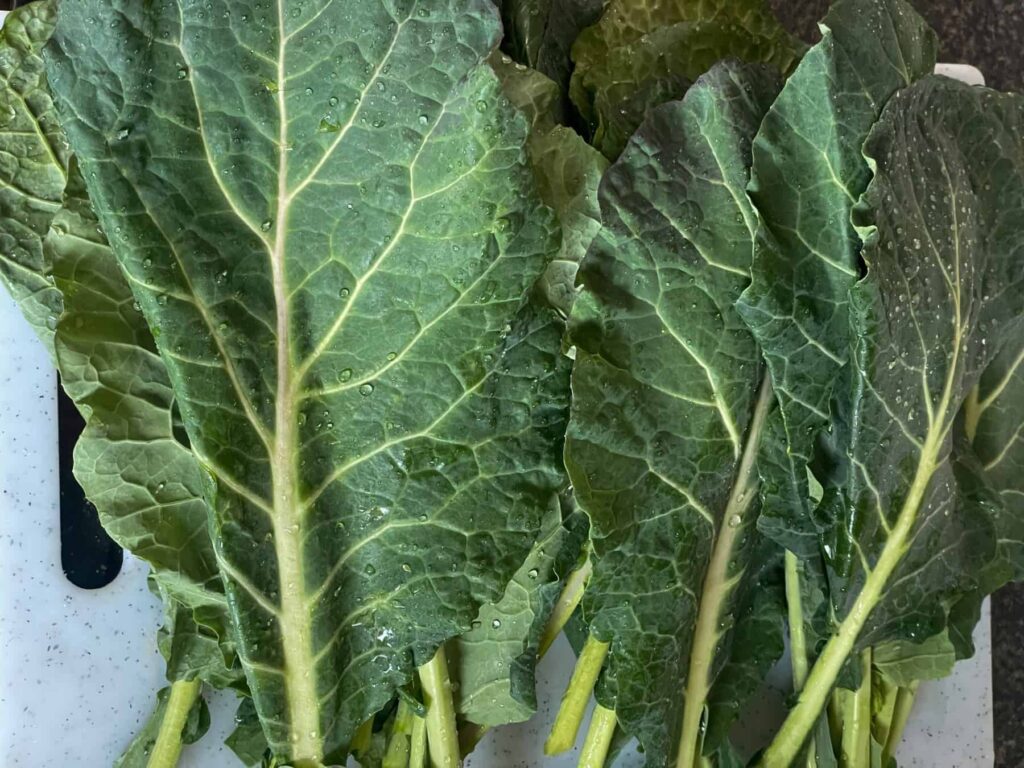 Greens leaves on white chopping board.