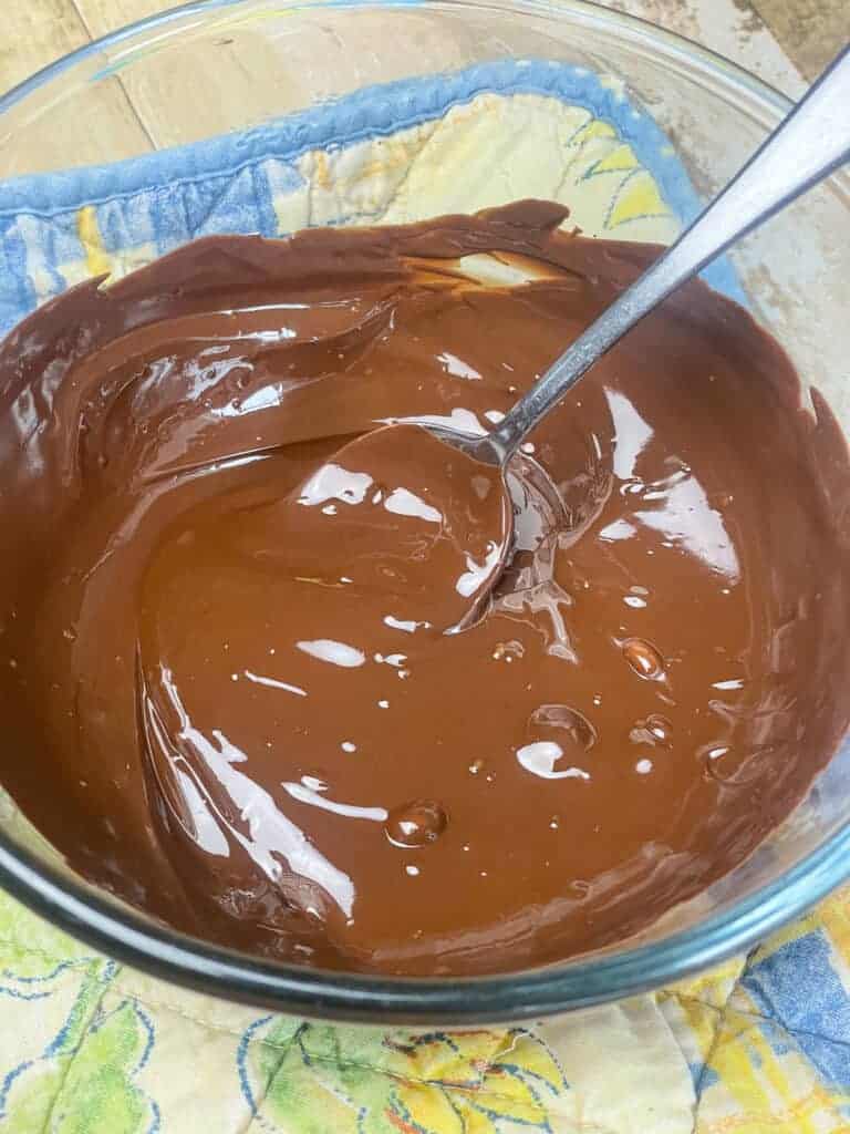 Dark chocolate melted and removed from pot and on yellow flower table mat.