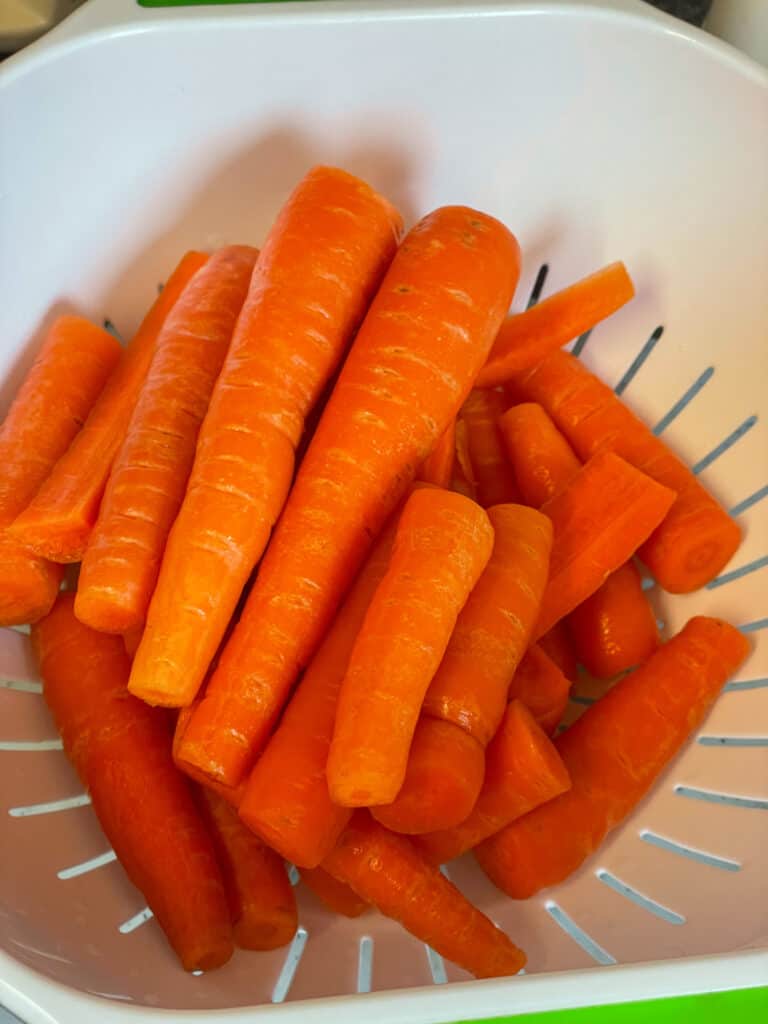 pile of carrots in a white colander.