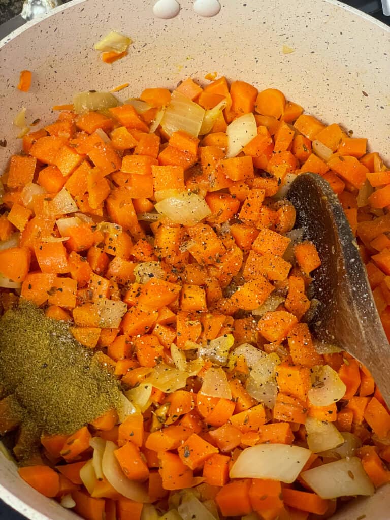 ground cumin added to sautéed veggies in pot.