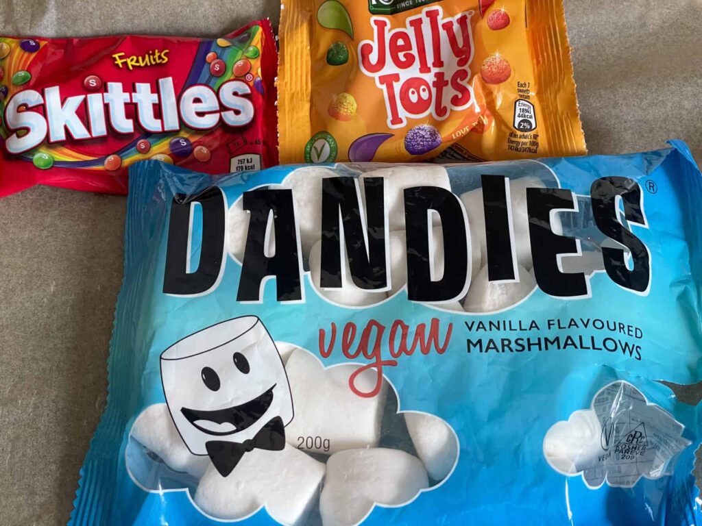 a packet of Dandies vegan marshmallows, small packet of Skittles and small packet of Jelly tot sweets.