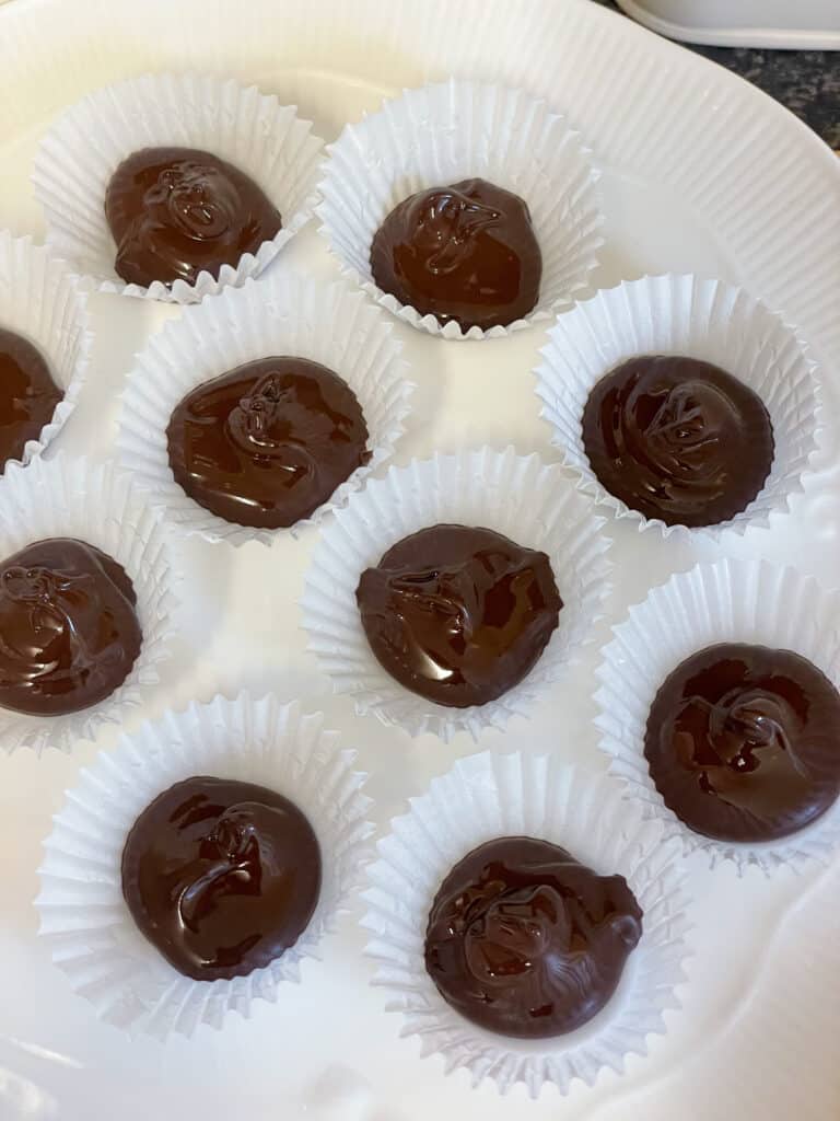 melted chocolate scooped into mini paper cases on a white plate.