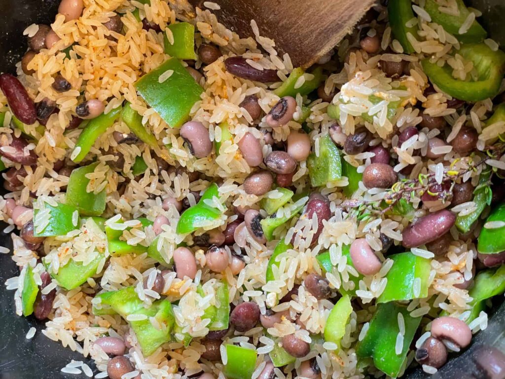 rice and peas ingredients in slow cooker mixed together with wooden spatula.