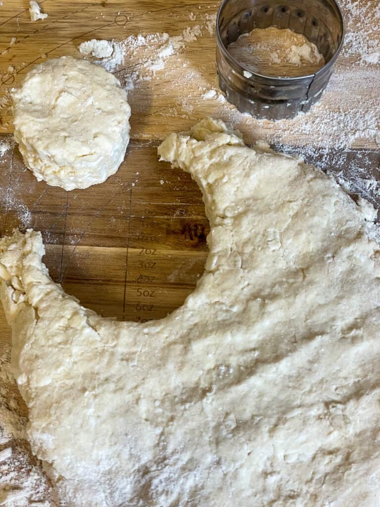 scone dough patted down and a scone stamped out with cookie cutter.