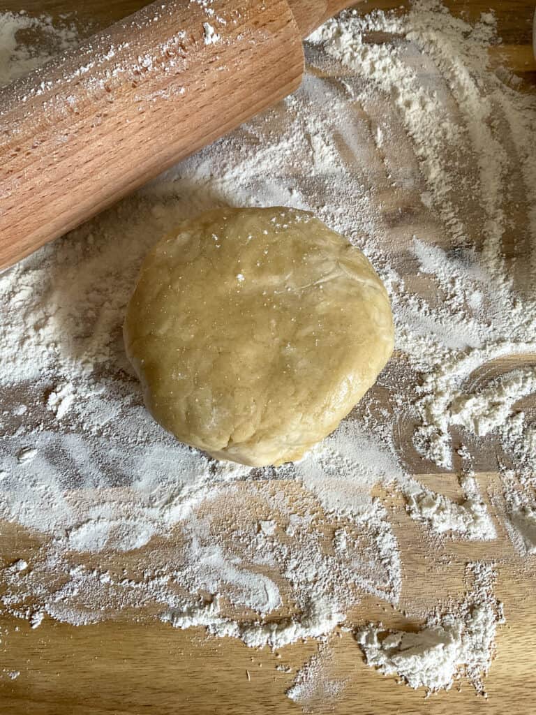 pastry ball on floured board with wooden rolling pin.