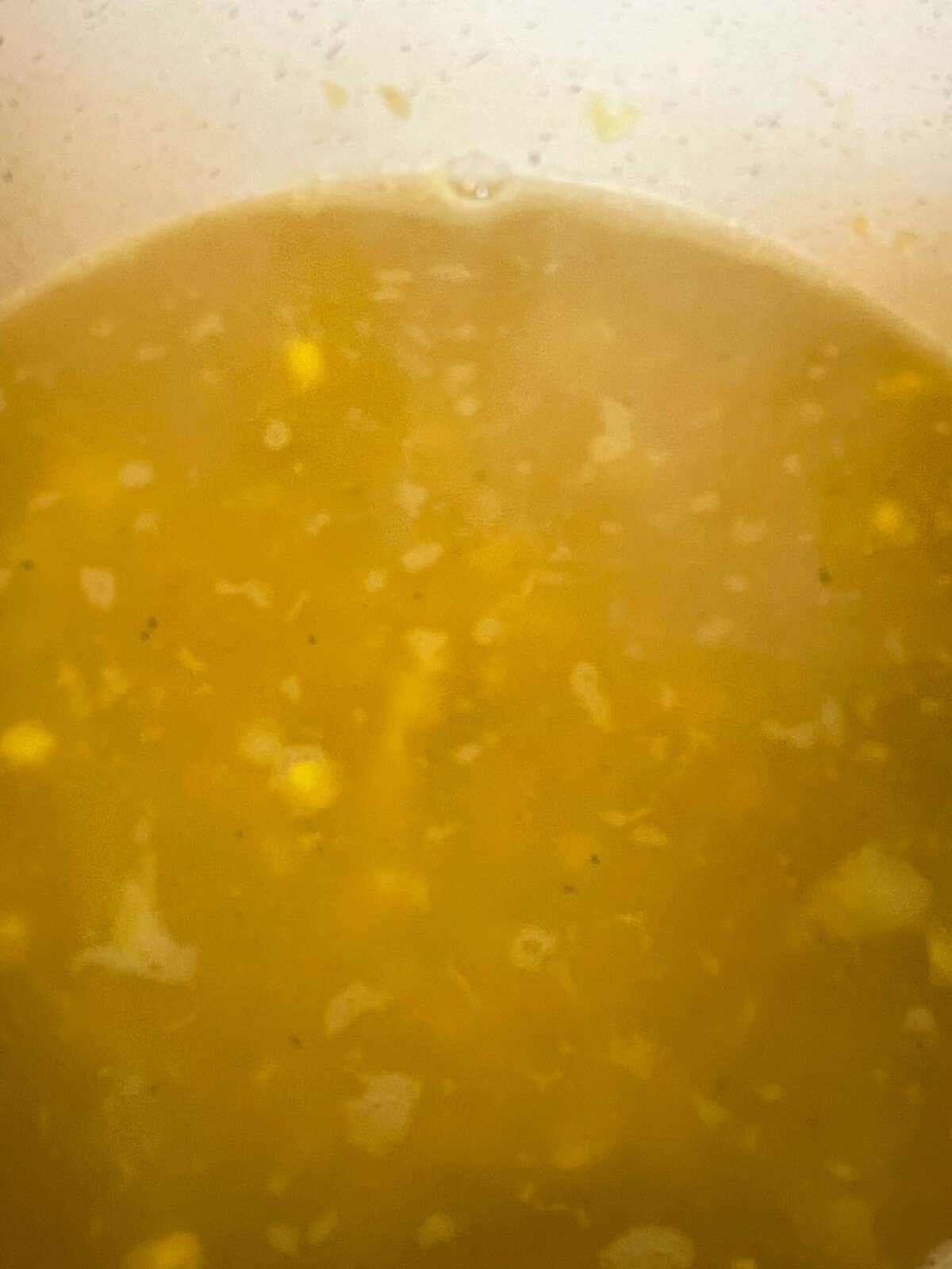 Veggie broth added to veggies cooking in soup pan.