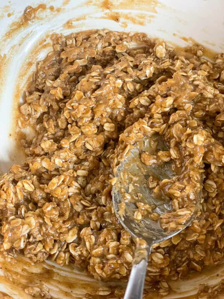 Oatmeal cookie mixed into unbaked dough in mixing bowl.