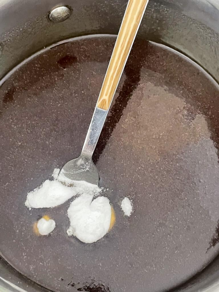 bicarbonate of soda sprinkled on top of the melted ingredients in saucepan with fork to side.