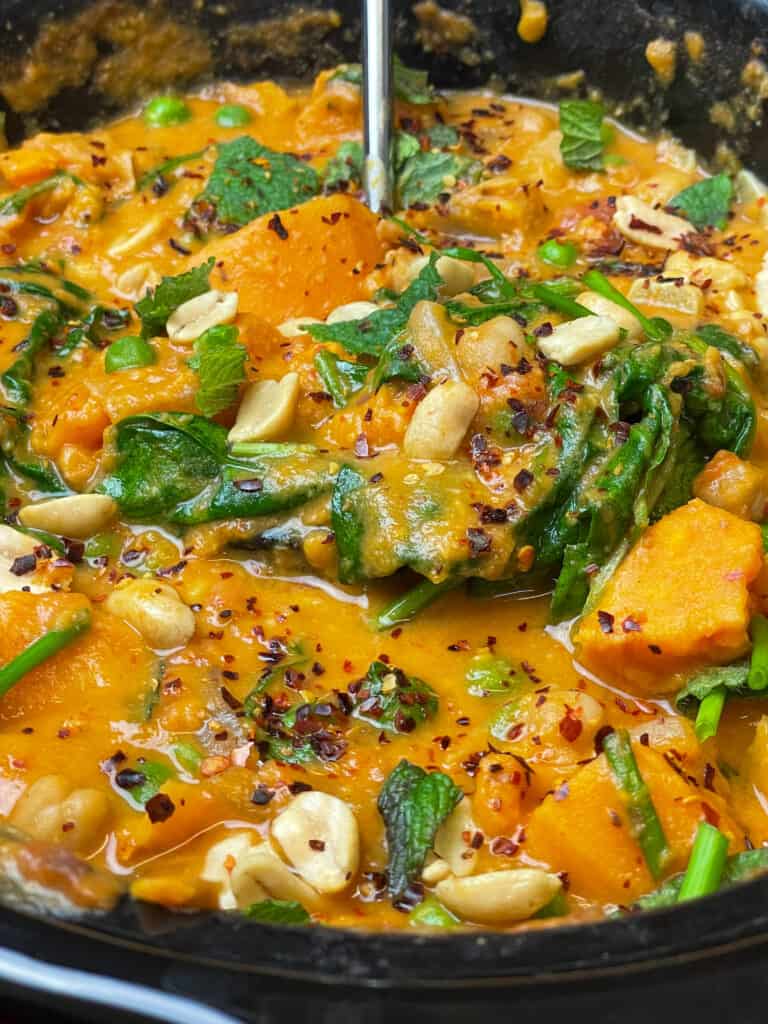 Close up of curry in the slow cooker with a serving ladle scooping up a portion ready to serve,.