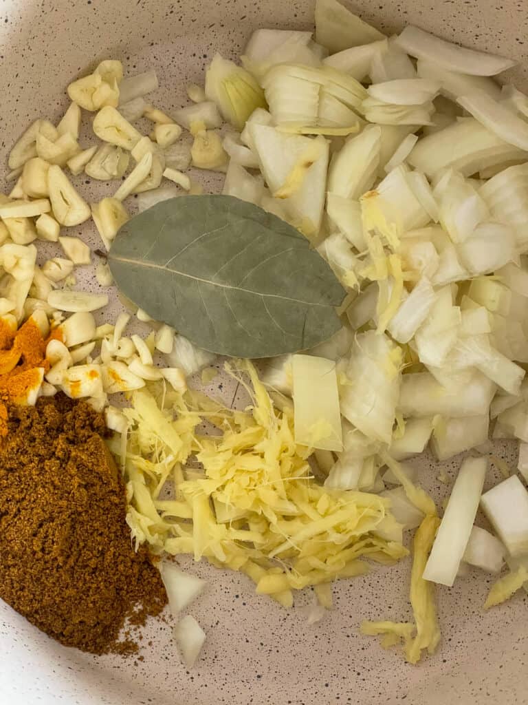 red lentil dahl ingredients added to saucepan.