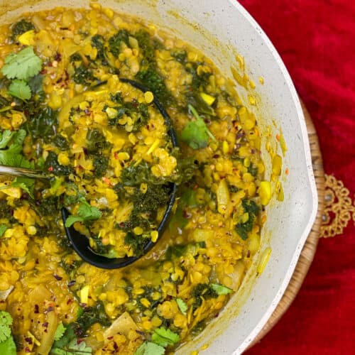 red lentil and kale dahl cooked in pan and ready to serve, red velvet background.