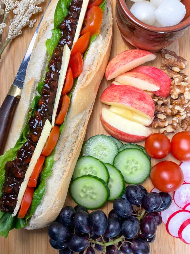 Grapes, and salad added to side of filled baguette.