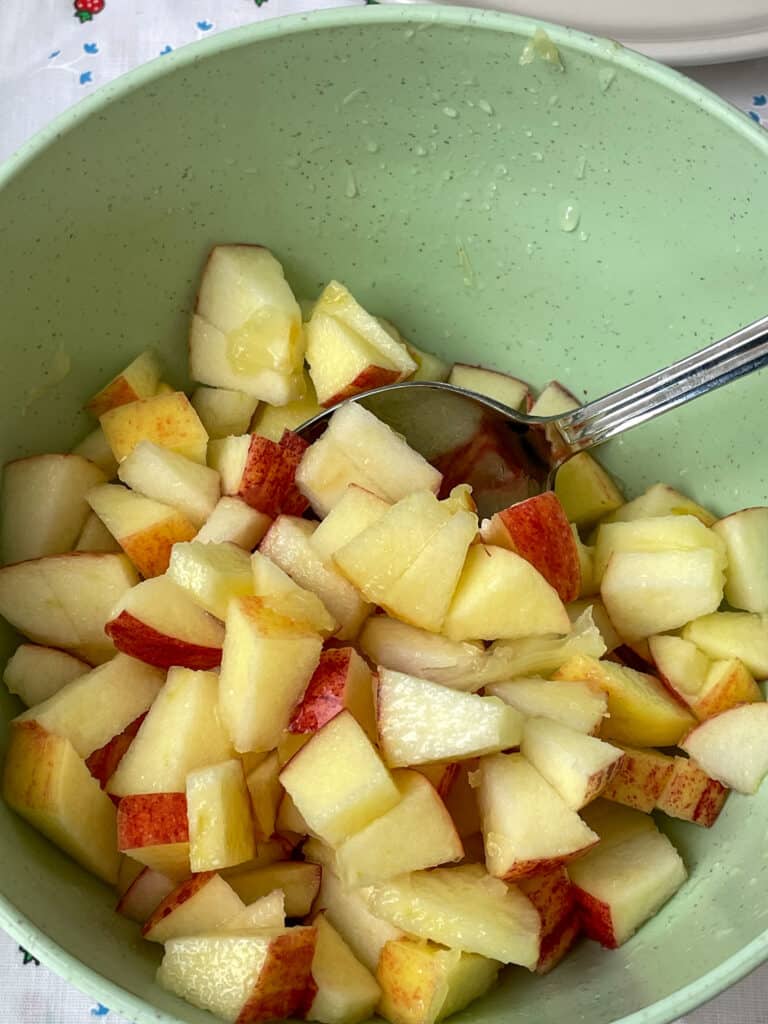 Apples diced and in bowl with silver spoon.