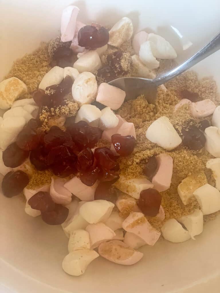 digestives, marshmallows and candied cherries added to mixing bowl with silver spoon.