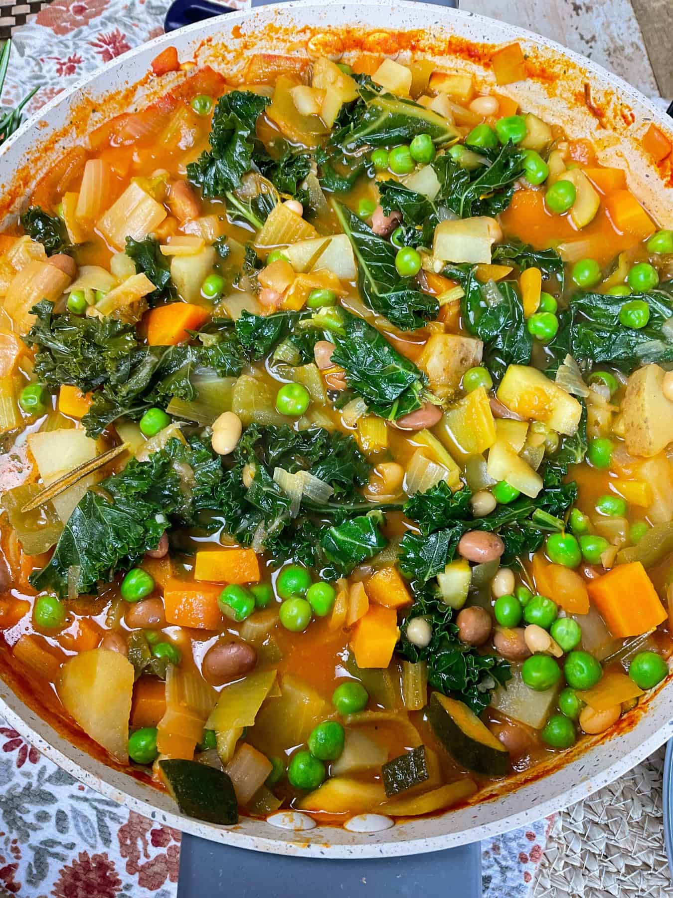 close up of zuppa di cavolo in soup pot, brown flower tea towel background.