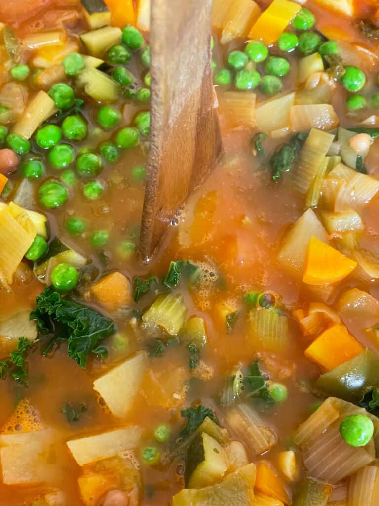 wooden spoon stirring cabbage and bean soup.