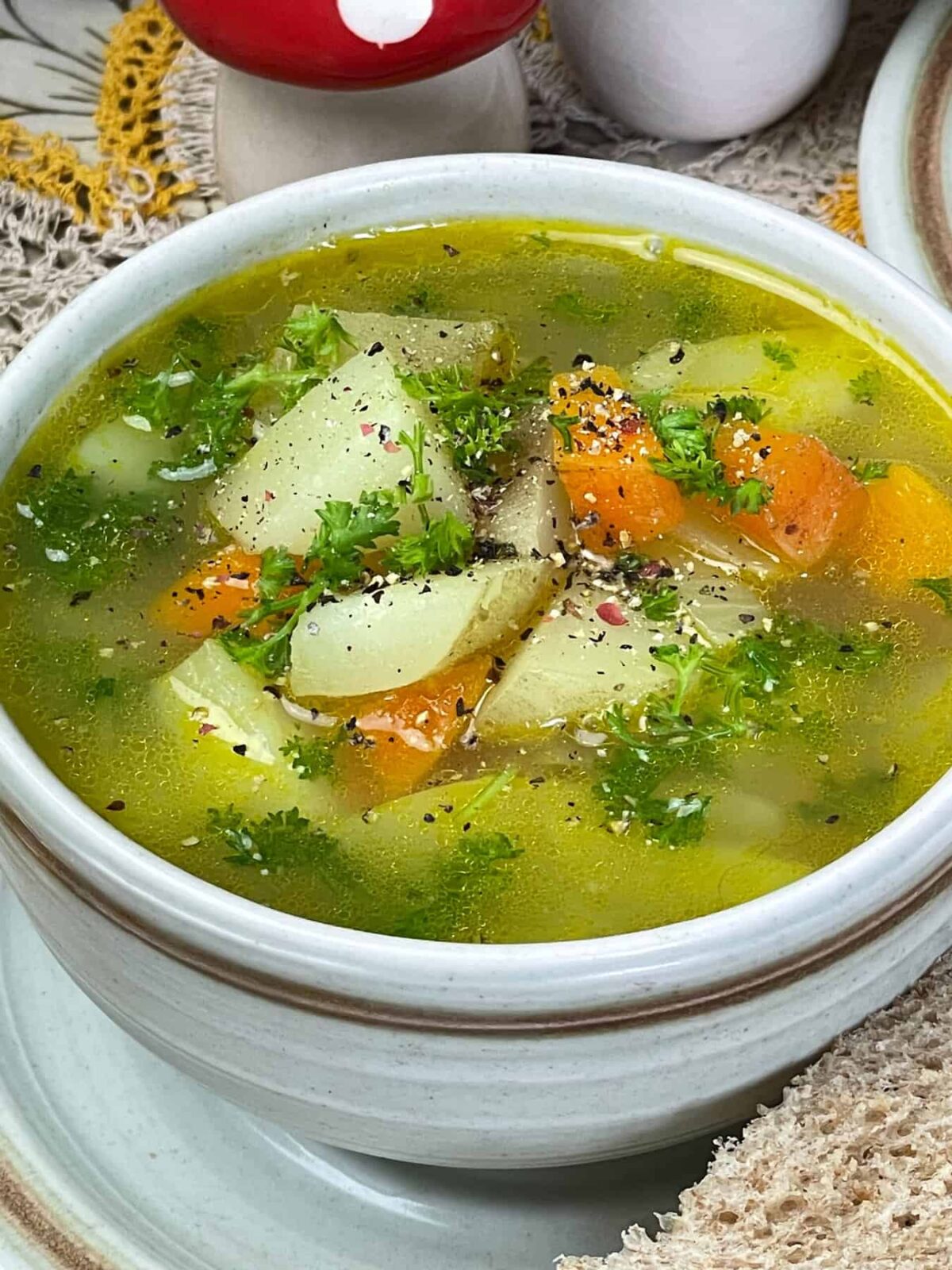 Close up of potato soup garnished with chopped parsley and colourful pepper corns.