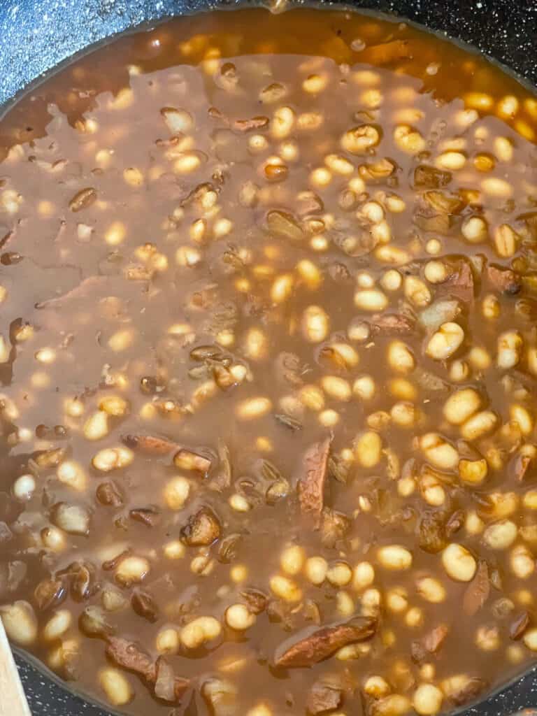 Hot stock poured into the beans in the frying pan.