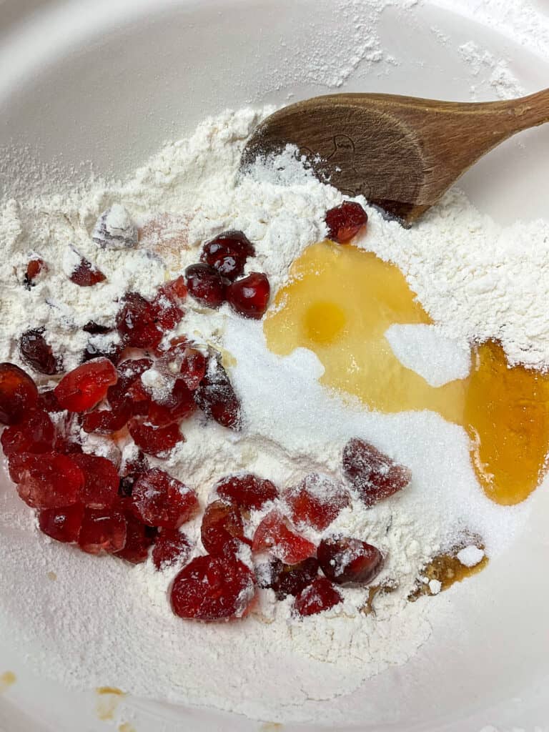 Dry ingredients for cherry loaf in mixing bowl with wooden spoon.