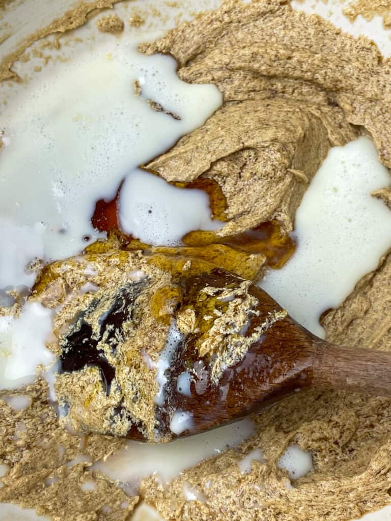 Golden syrup and milk added to creamed margarine in mixing bowl.