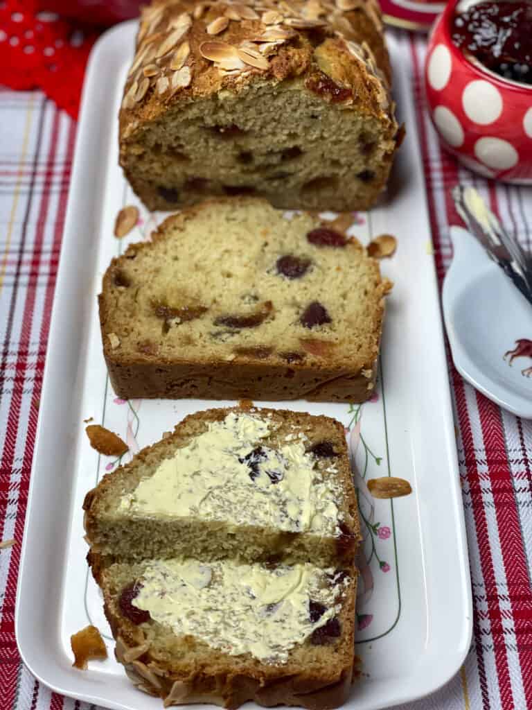 Bread sliced and on rectangular flower image tray, red and white stripe table cloth.