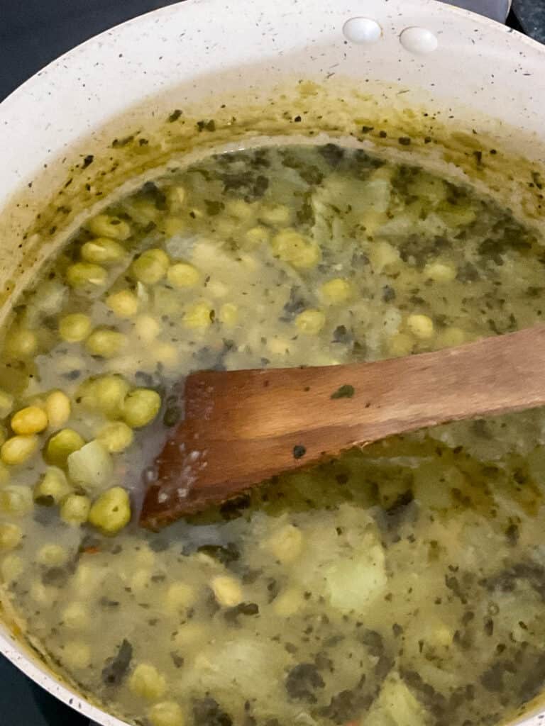 pea soup cooked and being stirred with wooden spoon.