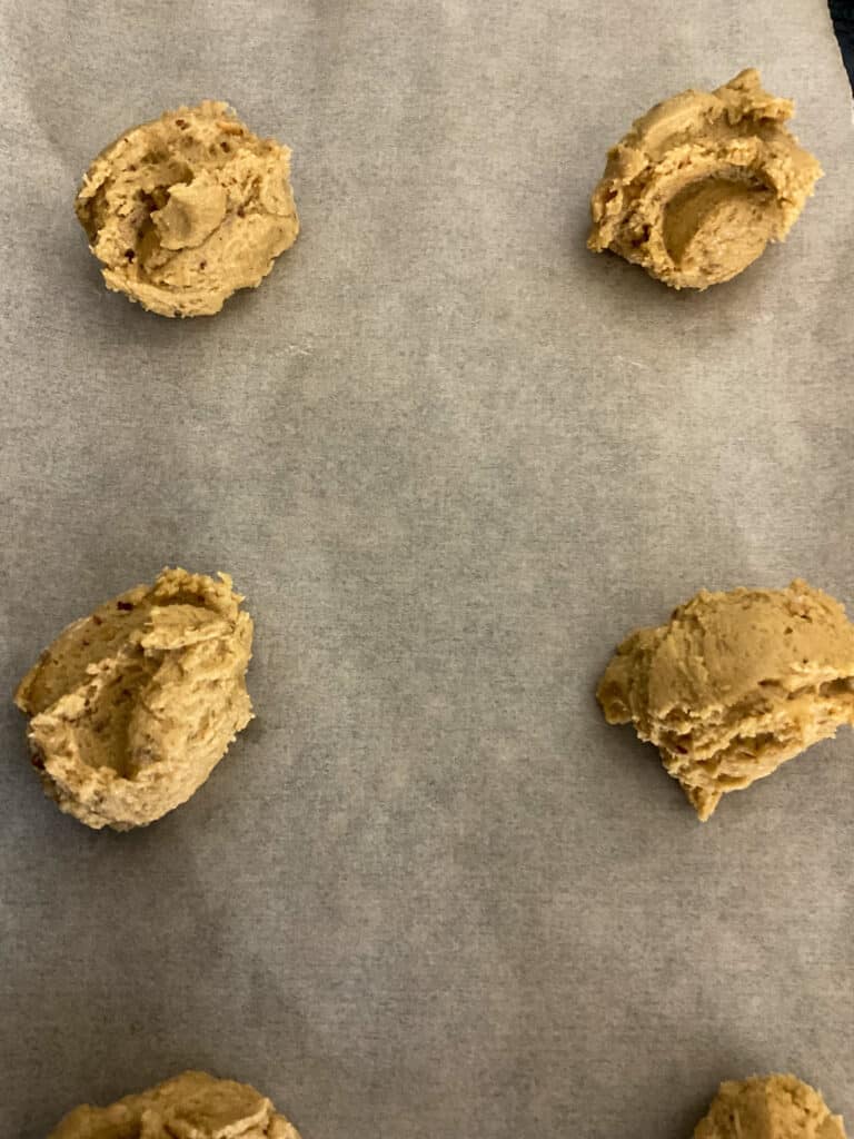 dollops of peanut butter dough on baking tray ready to bake.