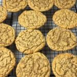 wire rack with 12 old-fashioned peanut butter cookies, yellow oven mitt to side.