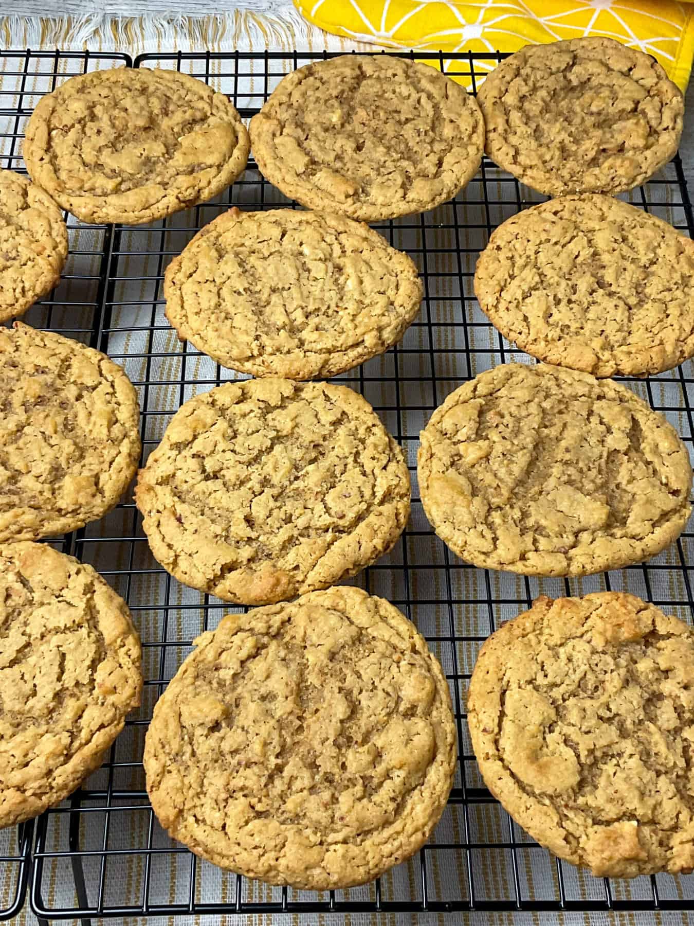 wire rack with 12 old-fashioned peanut butter cookies, yellow oven mitt to side.