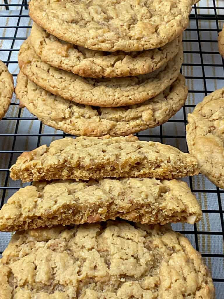 peanut butter cookies halved in two pieces so the insides can be seen, stack of cookies in background on wire rack.