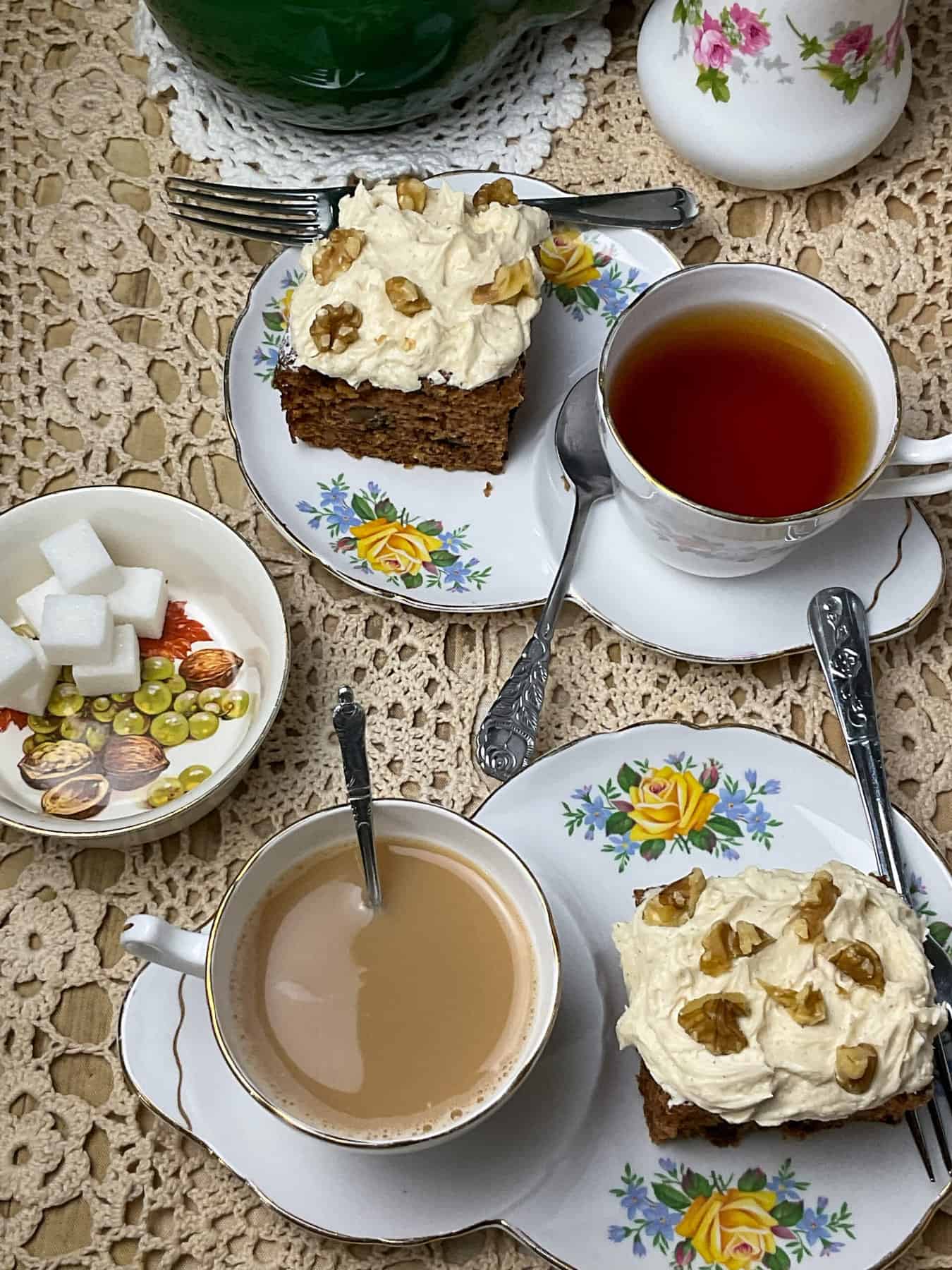 Afternoon tea table setting with tea cups and slices of cake.