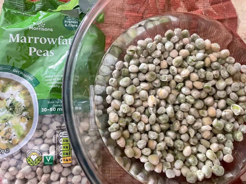 marrowfat pea packet beside glass bowl with peas soaking in water