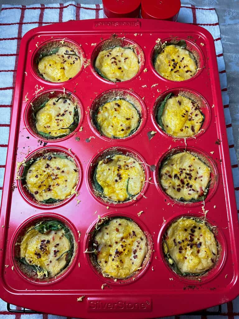 baked mini vegan quiche cups in red muffin pan on wire rack.