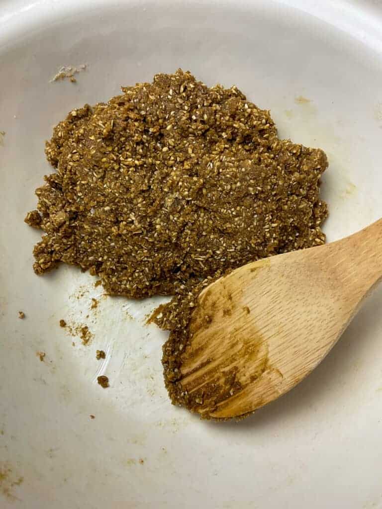 Ingredients mixed to form a cookie dough with wooden spatula in mixing bowl.