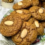 Traditional parkin biscuits on a flower patterned plate, with small sugar cube dish to side and white doily tablecloth.