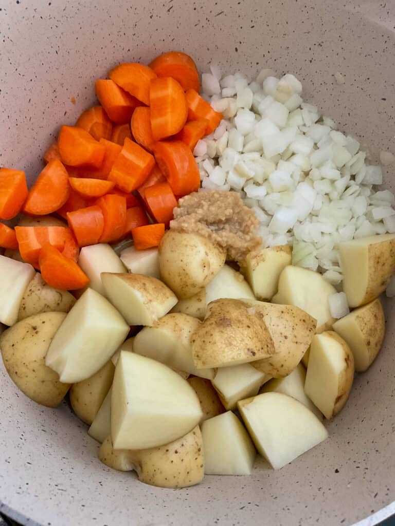 potatoes, carrots and onions added to stew pot for vegan meat and potato pie.