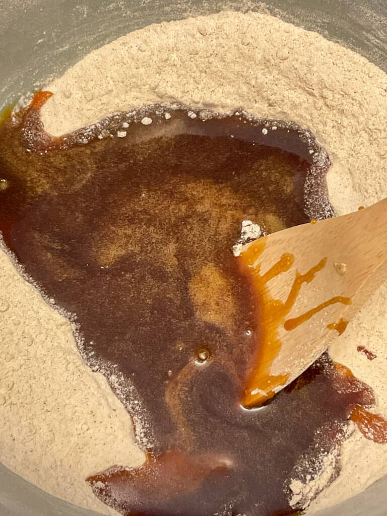 vegan gingerbread men ingredients in mixing bowl with wooden spatula.