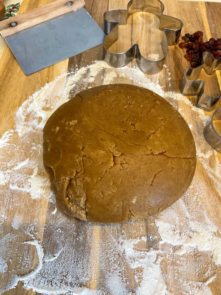 cookie dough ball on floured board with cookie cutters to side.