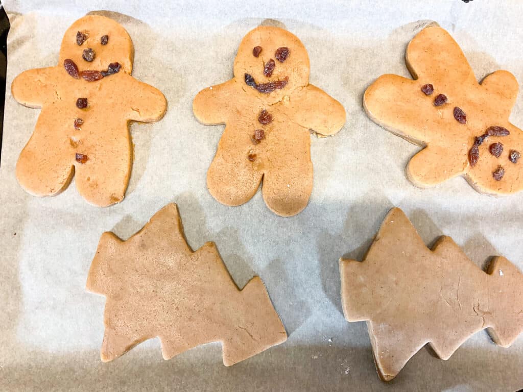 large gingerbread men and gingerbread Christmas trees on baking tray, unbaked.