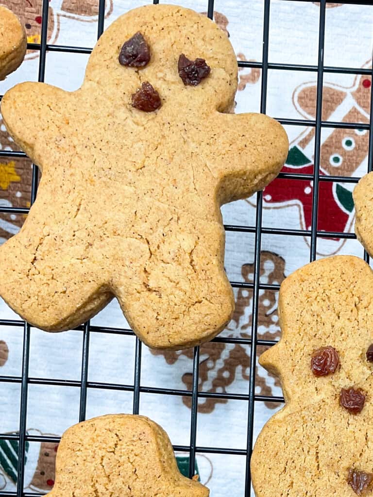 gingerbread men cooling on a wire rack with tea towel underneath with gingerbread men images.