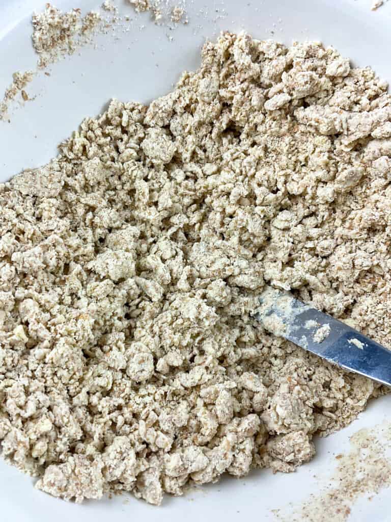 Water added to flour breadcrumb mixture and stirred with a cutlery knife until pastry clumps formed.